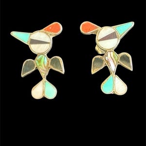 May include: A pair of bird-shaped earrings with inlaid turquoise, red, and abalone shell accents. The earrings have a silver-tone metal frame and a whimsical design. The birds have a white body, turquoise wings, and a red crest.
