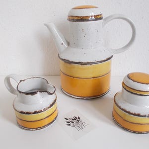 Op de afbeelding: Een witte keramische mok met een zwarte handgreep en de tekst "But First, Coffee" in een zwarte, vette letter. De mok is ongeveer 10 cm hoog en kan ongeveer 350 ml vloeistof bevatten.