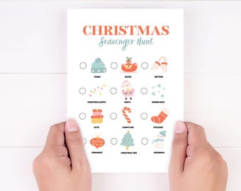May include: A white Christmas scavenger hunt game card with illustrations of holiday items like a toque, sleigh, and snowman. The card is held by two hands and features the text "CHRISTMAS Scavenger Hunt".