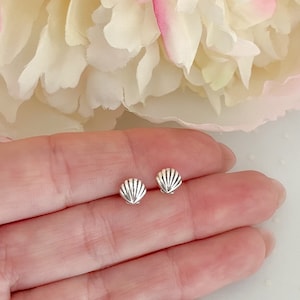 May include: A pair of silver shell stud earrings. The earrings are small and delicate, and they are perfect for everyday wear.