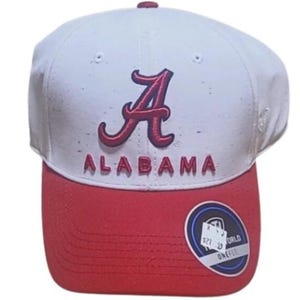 Peut inclure: Casquette de baseball blanche et rouge avec le mot "ALABAMA" brodé en rouge. La casquette présente un logo "A" rouge et une visière rouge. Un autocollant circulaire est sur la visière.