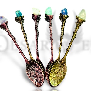 May include: Set of five ornate metal teaspoons with colorful crystal tops. Each spoon has a floral design and a different colored crystal.