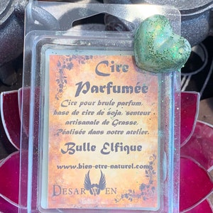 Peut inclure: Un fondant de cire de soja en forme de cœur vert dans un récipient en plastique transparent. Le fondant est étiqueté "Cire Parfumée" et "Bulle Elfique". L'étiquette comprend également le texte "Cire pour brule parfum, base de cire de soja, senteur artisanale de Grasse, Réalisée dans notre atelier." et "www.bien-etre-naturel.com".