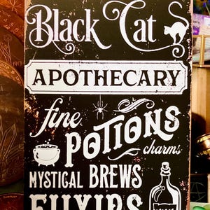 May include: Black Cat Apothecary sign with white lettering on a black background. The sign features the words "Black Cat", "Apothecary", "Fine Potions", "Mystical Brews", and "Elixirs". A cat silhouette and potion bottle are also included.