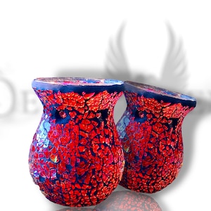 Könnte beinhalten: Zwei rote und schwarze Mosaik-Kerzenhalter aus Glas. Die Halter sind rund und haben eine breite Basis. Sie bestehen aus kleinen Glassplittern, die in einem zufälligen Muster angeordnet sind.