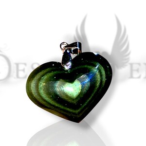 Peut inclure: Pendentif en forme de cœur avec une bélière argentée. Le pendentif est fait d'un matériau vert foncé irisé avec des motifs tourbillonnants et une surface réfléchissante. Le pendentif est sur fond blanc.