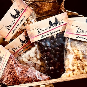 Könnte beinhalten: Fünf kleine Beutel mit Räucherwerk mit Etiketten in Französisch. Die Etiketten lauten "DESAR EN" und listen die Art des Räucherwerks in jedem Beutel auf: "Aeurs de Jasmin", "Bois de Santal rouge", "Encens Thibétais", "Baie de Genévrier" und "Résine Jérusalem".