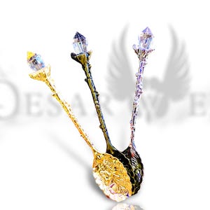 May include: Three ornate spoons with crystal-shaped handles. The spoons are gold, silver, and black.