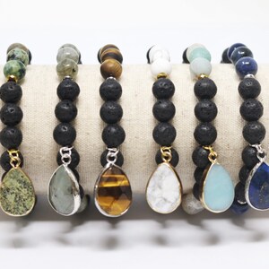 Può includere: Sei braccialetti di perline con perline di roccia lavica nera e ciondoli a forma di goccia. I ciondoli sono in vari colori, tra cui verde, grigio, marrone, bianco, azzurro e blu scuro, con finiture in metallo color oro o argento.