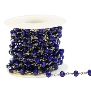 Peut inclure: Une bobine de chaîne bleue et argentée avec des perles. La chaîne est enroulée autour d'une bobine en plastique blanc. Une petite partie de la chaîne est étendue de la bobine.
