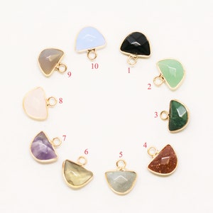 May include: Ten different semi-circle shaped gemstone charms with gold jump rings. The gemstones are in various colors including light blue, black, green, pink, purple, yellow, brown, and gray.