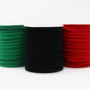 May include: Three spools of elastic cord in green, black, and red. The cord is wound tightly around each spool.