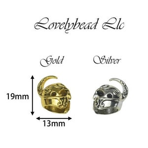 May include: Two Viking helmet beads, one gold and one silver, measuring 13mm wide and 19mm tall. The beads are detailed with intricate designs and are perfect for jewellery making.