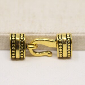 May include: Gold-toned metal clasp with decorative beading. The clasp is designed for use with cords or straps.