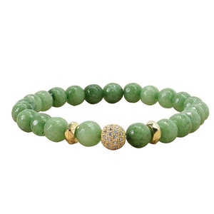 May include: A green gemstone beaded bracelet with a gold and clear crystal accent bead.