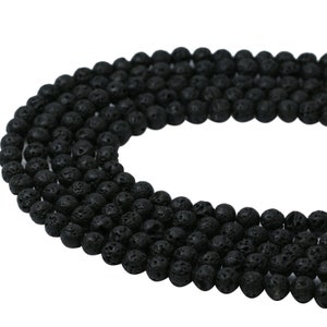 May include: A strand of black lava rock beads. The beads are round and have a rough, textured surface.