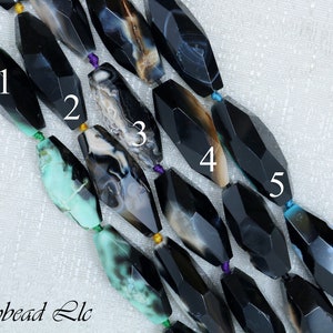 May include: Five black agate beads with different patterns and colors. The beads are faceted and have a polished finish. The beads are numbered 1 through 5.
