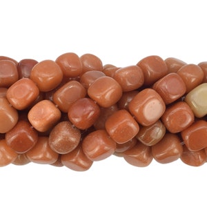 May include: A strand of smooth, tumbled carnelian beads in a warm orange-brown color. The beads are all roughly the same size and shape, and they have a slightly irregular, natural look.