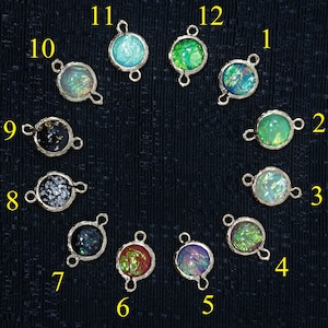 May include: Twelve round, iridescent glass charms with gold-toned metal loops. The charms are numbered 1 through 12.
