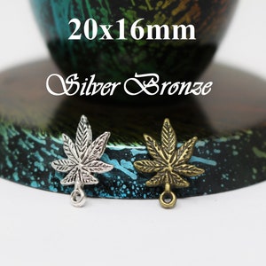 May include: Two marijuana leaf charms, one silver and one bronze, with a loop at the bottom. The charms are 20mm x 16mm.