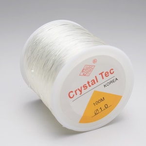 May include: A spool of clear elastic string, 100 meters long and 1.0 mm in diameter, labeled "Crystal Tec Korea".