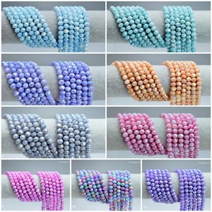 Puede incluir: Surtido de cuentas de cristal en varios colores, incluyendo azul claro, lavanda, gris, rosa e iridiscente. Las cuentas son facetadas y tienen forma redonda.