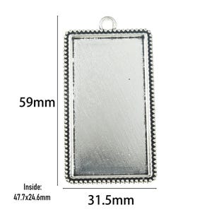 May include: A rectangular silver-toned metal pendant tray with a beaded border and a top loop. The total height is 59mm and the width is 31.5mm. The inner dimensions of the tray are 47.7mm by 24.6mm, as indicated by the text in the image.