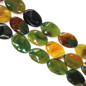 May include: A strand of polished oval beads featuring a marbled pattern in shades of forest green, mustard yellow, deep brown, and black. Each bead has a smooth, glossy finish with unique color swirls and natural banding visible throughout the surface.