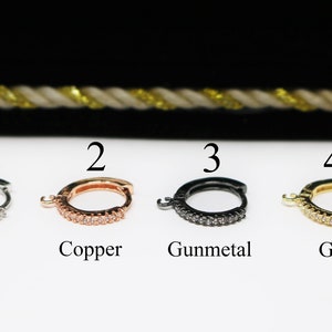 May include: Four hoop earrings with a row of clear rhinestones. The hoops are in silver, copper, gunmetal, and gold.