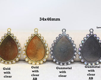 Könnte beinhalten: Vier tropfenförmige Anhänger-Einstellungen, jede misst 34 mm x 46 mm. Zwei Einstellungen sind goldfarben mit klaren Strasssteinen, eine ist goldfarben mit klaren AB-Strasssteinen und zwei sind gunmetalfarben mit klaren Strasssteinen.