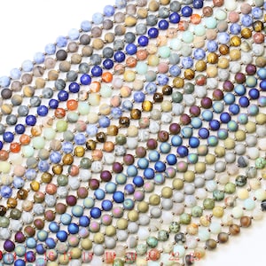Peut inclure: Une collection de 23 brins de perles rondes en pierres précieuses. Les perles sont de différentes couleurs, notamment le bleu, le vert, le marron et le gris. Les perles sont disposées en rangées, avec les numéros 1 à 23 imprimés sous chaque rangée.
