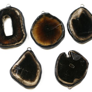 May include: Five black and brown agate pendants with silver jump rings. The pendants are all different shapes and sizes, and some have a more polished finish than others.