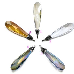 May include: Five crystal teardrop pendants with silver settings and black accents. The pendants are in various colors, including clear, gold, blue, and iridescent.