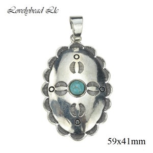 Könnte beinhalten: Silberner ovaler Anhänger mit einem Türkis-Stein und einem komplizierten Design. Der Anhänger misst 59x41 mm.