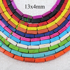 Könnte beinhalten: Nahaufnahme einer Regenbogen-Auswahl von 13 rechteckigen Türkisperlen, jede misst 13 mm x 4 mm. Die Perlen sind in einem Halbkreis angeordnet, wobei die größte Perle oben und die kleinste Perle unten ist.