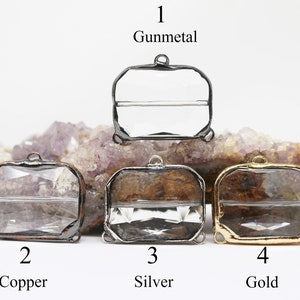 Puede incluir: Cuatro bandejas de colgantes de vidrio con diferentes acabados metálicos: bronce oscuro, cobre, plata y oro. Cada bandeja tiene una forma rectangular con un inserto de vidrio transparente y dos bucles a cada lado.