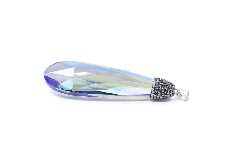 May include: A teardrop-shaped crystal pendant with a silver-toned metal setting. The crystal is iridescent and has a blue, green, and purple hue.