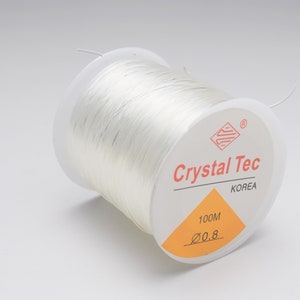 May include: A spool of white elastic cord, labeled "Crystal Tec Korea" and "100M 0.8".