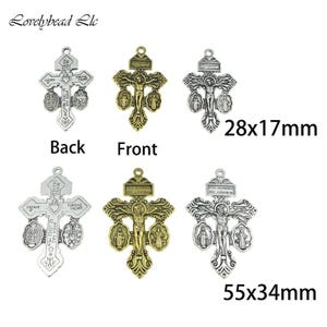 Puede incluir: Una colección de colgantes de cruz religiosos en tonos plateados y dorados. Los colgantes presentan detalles intrincados, incluyendo la crucifixión de Jesús y figuras religiosas. Las dimensiones son 28x17mm y 55x34mm.