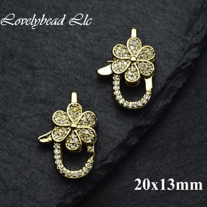 May include: Two gold-tone flower-shaped clasps with clear rhinestones. Each clasp measures 20x13mm.