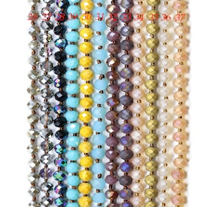 May include: A close-up of 12 strands of faceted glass beads in various colors, including silver, black, turquoise, yellow, light blue, purple, beige, gold, and pink. The beads are strung on a thin wire and are arranged in a vertical row.