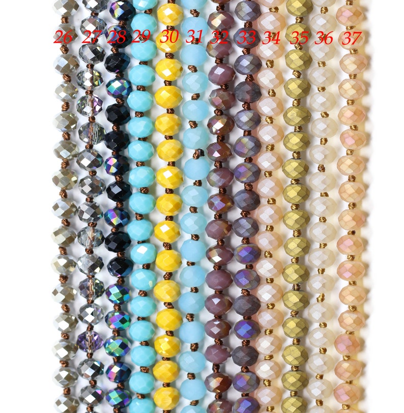 May include: A close-up of 12 strands of faceted glass beads in various colors, including silver, black, turquoise, yellow, light blue, purple, beige, gold, and pink. The beads are strung on a thin wire and are arranged in a vertical row.