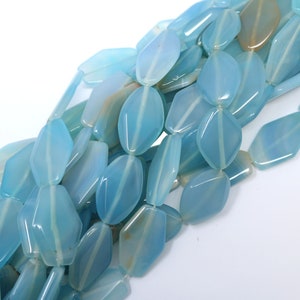 Op de afbeelding: Een streng lichtblauwe edelsteen kralen, elke kraal is gefacetteerd en heeft een licht onregelmatige vorm.