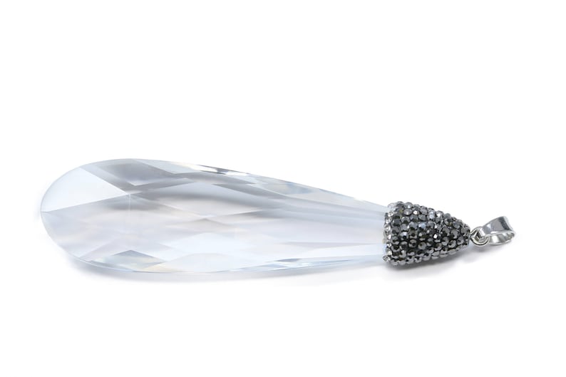 May include: A clear crystal teardrop pendant with a silver bail and a black rhinestone-encrusted cap.