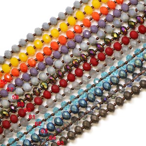May include: A close-up of a strand of beads with various colors and textures. The beads are arranged in rows, with each row featuring a different color and style. The colors include gray, orange, red, blue, and brown. The beads are made of glass and have a faceted design.