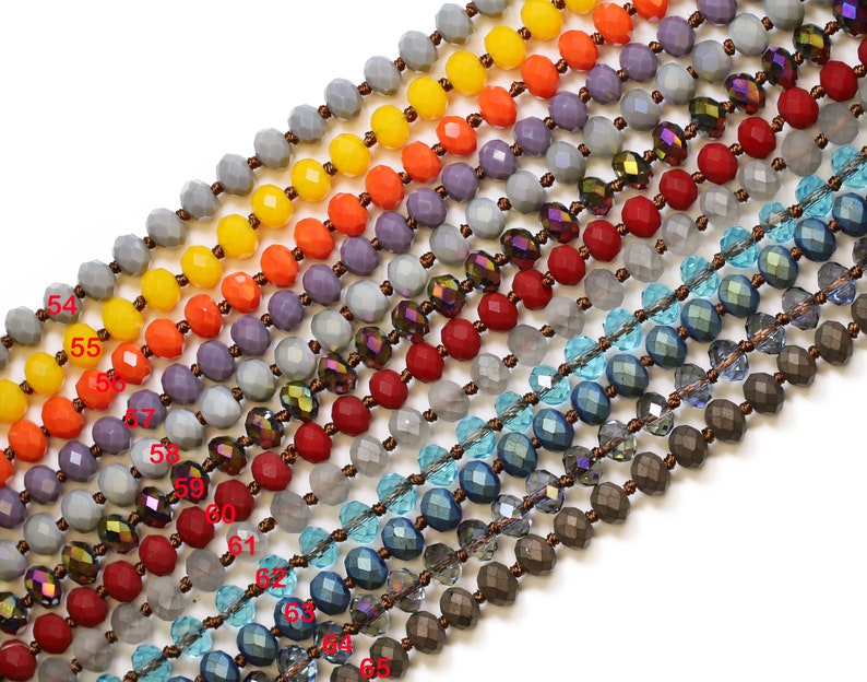 May include: A close-up of a strand of beads with various colors and textures. The beads are arranged in rows, with each row featuring a different color and style. The colors include gray, orange, red, blue, and brown. The beads are made of glass and have a faceted design.