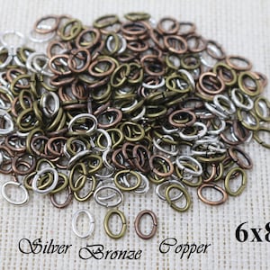 May include: A large pile of oval jump rings in silver, bronze, and copper colours. The rings are 6x8mm in size.