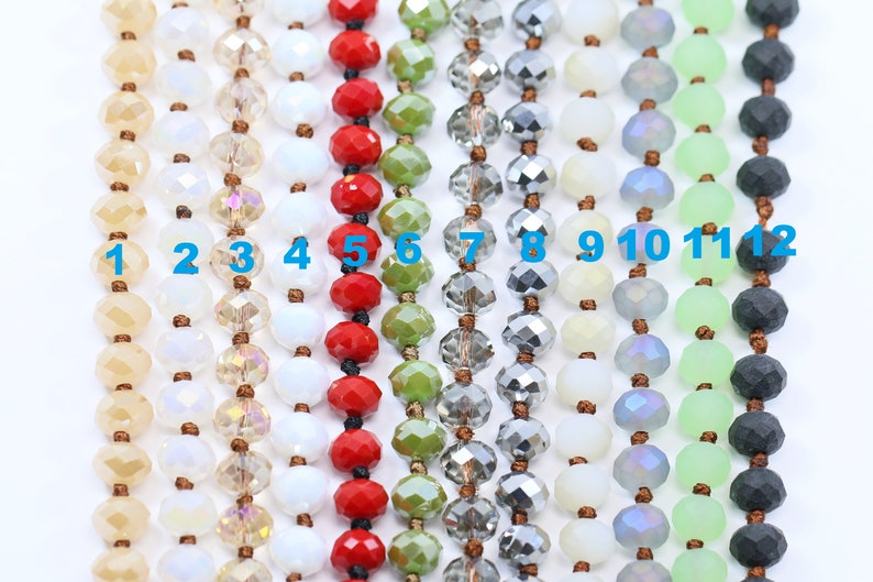 May include: Twelve strands of beads in various colors and finishes, including beige, white, red, green, gray, and black. The beads are numbered 1 through 12.