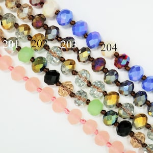 May include: Five strands of beads in different colors, including pink, green, gold, black, and blue. The beads are all faceted and have a shiny finish. The strands are labeled with numbers 200 through 204.