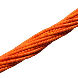 Puede incluir: Una hebra de cuentas cilíndricas de color naranja brillante, hechas de coral natural, dispuestas en espiral.